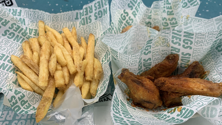 Wingstop wings and fries spread out on a number of wrapping papers