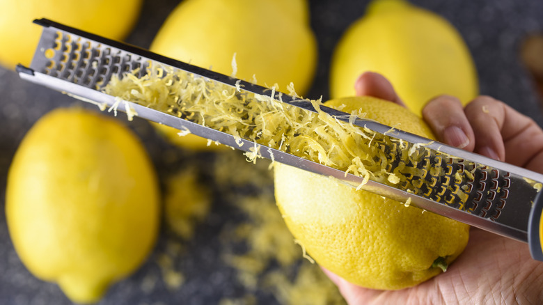 hand zesting lemon with microplane