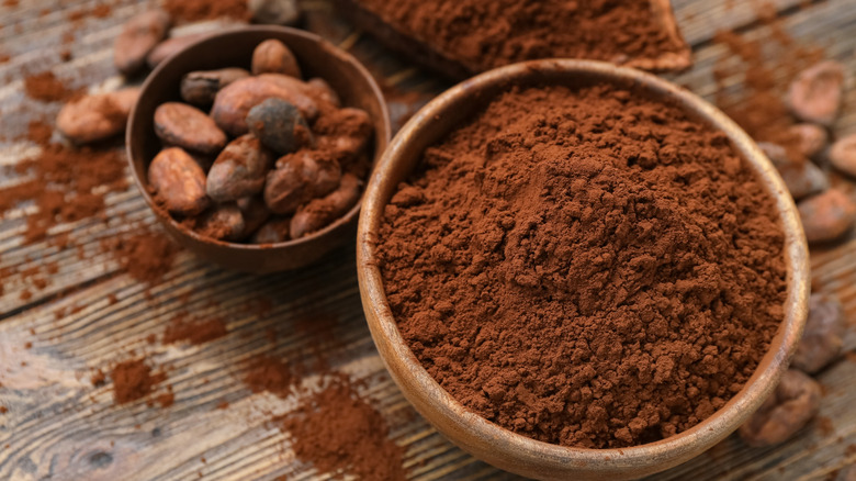 bowl of cocoa powder with beans on wooden table