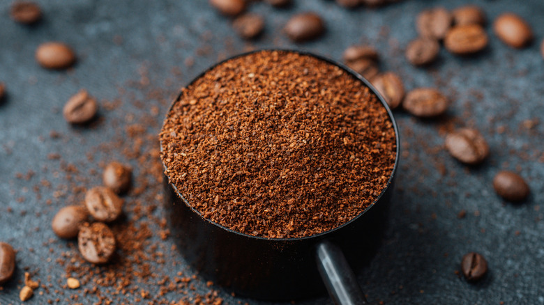 espresso powder in a measuring cup with beans in the background