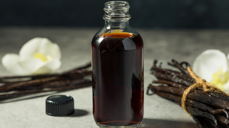 open bottle of vanilla extract with vanilla beans on the side