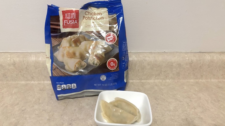 A bag of frozen chicken pot stickers and in a white bowl.