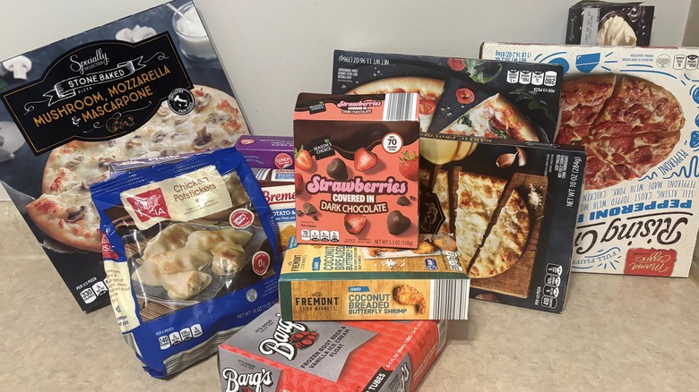 A variety of frozen foods from Aldi on a neutral background.
