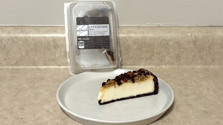Turtle cheesecake in container and on plate on a neutral background.