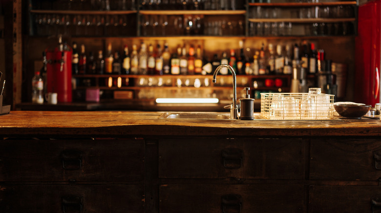 A long wooden bar with glasses and bottles