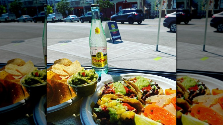 Plates of tacos and a Topo Chico in the window of a Seattle eatery