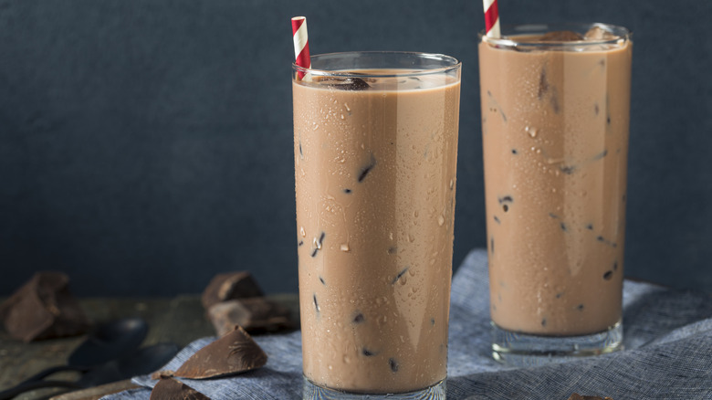 Two glasses of chocolate milk with chocolate chunks mixed in