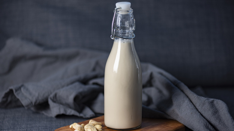 Glass bottle of cashew milk alongside cashews