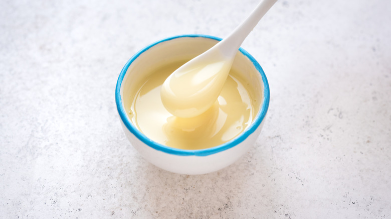 Sweetened condensed milk being scooped from a small bowl