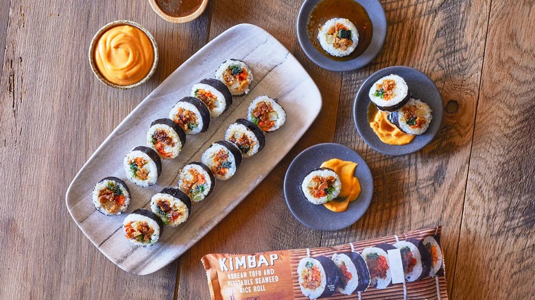 Trader Joe's Kimbap in package, on black plates, and on serving tray, sauces around