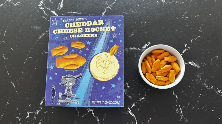 Trader Joe's cheddar cheese rocket crackers box next to rocket crackers in bowl