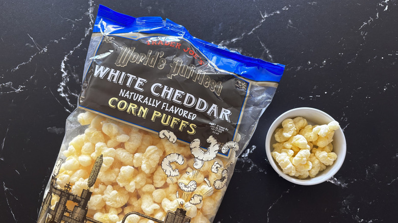 Trader Joe's white cheddar corn puffs bag next to bowl of corn puffs