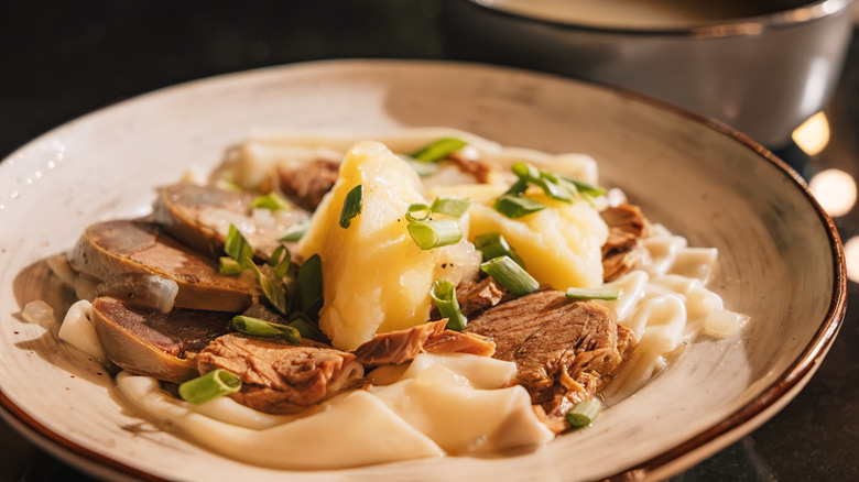 a close up of a bowl of beshbarmak with kazy sausage