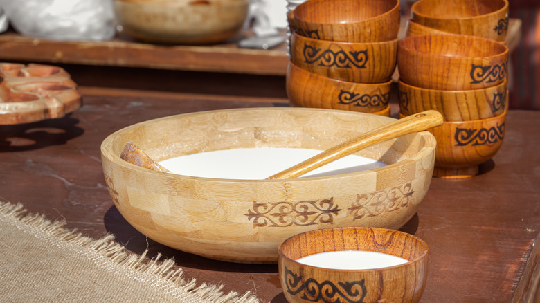 a large wooden bowl of kumis next to smaller bowls