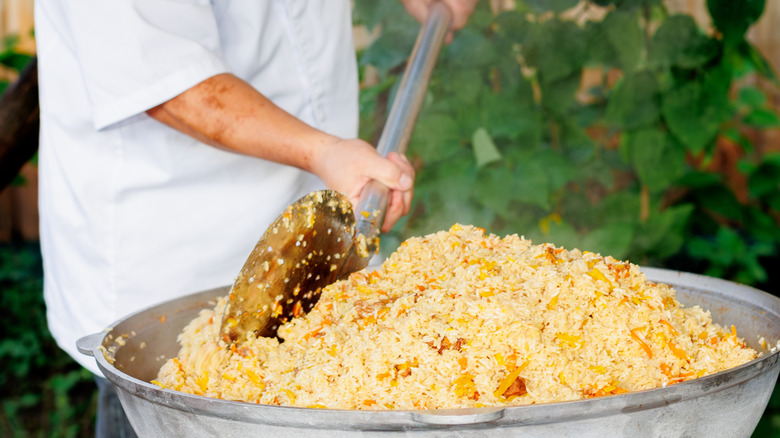 a man stirring a huge vat of plov