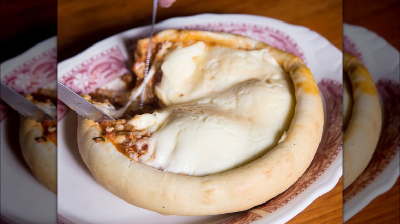 hands with knife and fork cutting a pizza pot pie