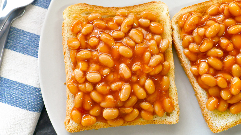 A plate of beans on toast set on a blue and white tablecloth.