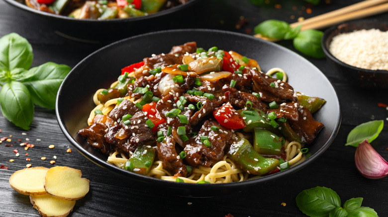 Stir-fried beef in black bean sauce with noodles in a bowl.
