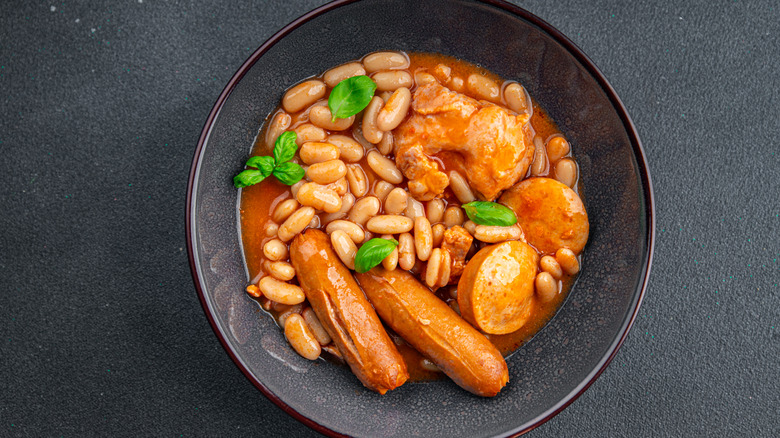 A bowl of cassoulet set against a dark background.