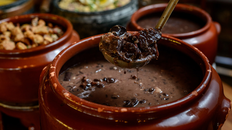 Feijoada being served from brown pot