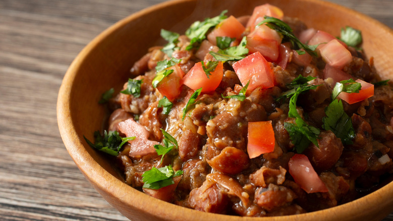 A brown bowl of Ful Mudammas on table.
