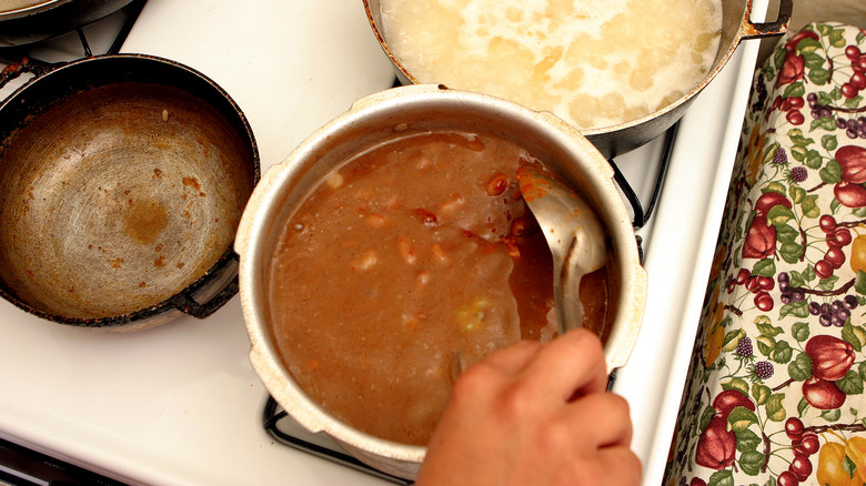 A cook stirring a pan of beans on the hob.