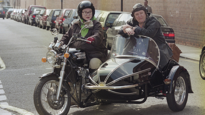 Jennifer Paterson and Clarissa Dickson in the street in their motorbike and sidecar