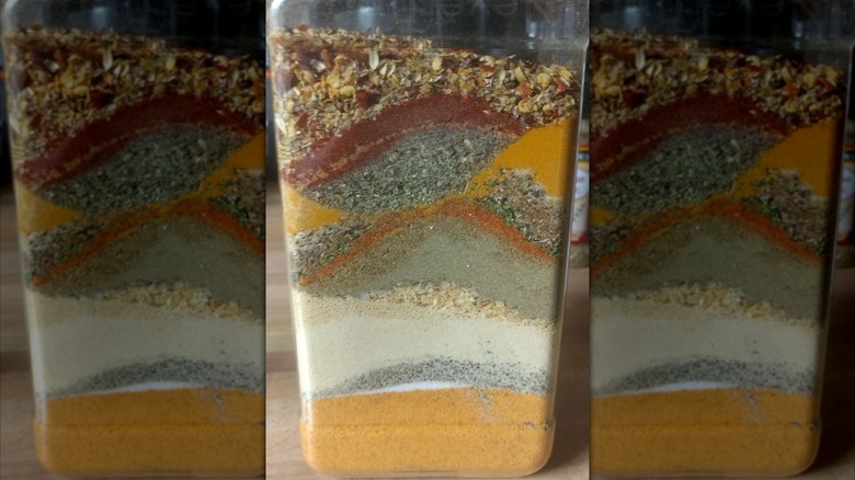 A spice jar holds a layered blend of spices.