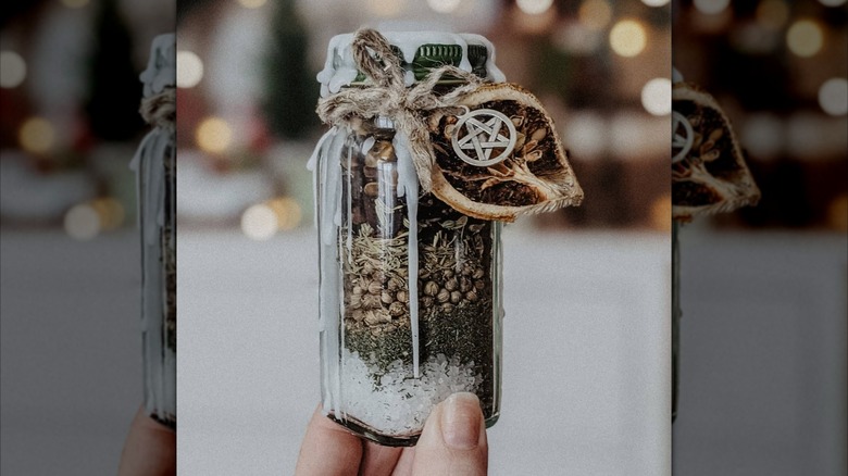 A spice har holds seeds and picts and has a charm on the side and melted wax on the top.