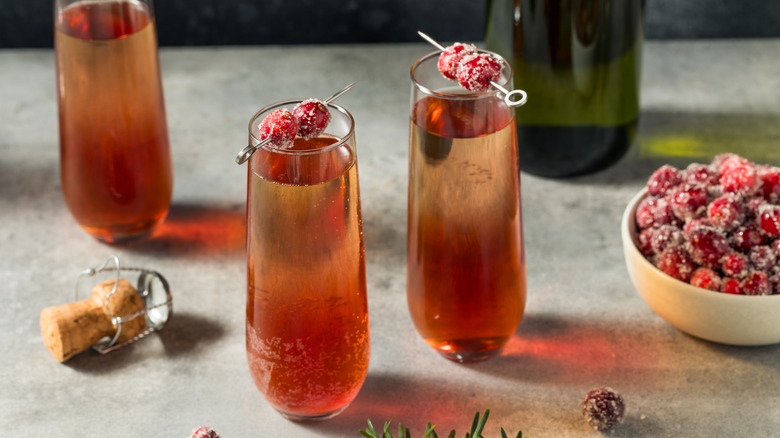 Three poinsettia cocktails with sugared cranberry garnishes