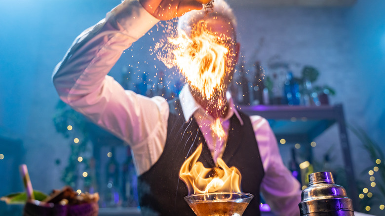 Bartender lighting a cocktail on fire at the bar