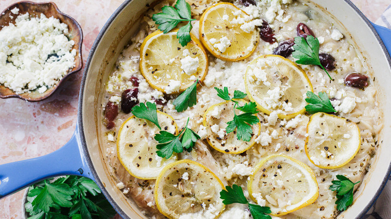 Pan of baked fish orzo topped with lemon rounds and fresh parsley
