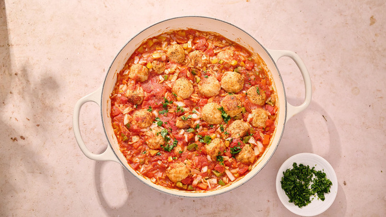Meatball orzo bake in casserole pot with fresh herb garnish