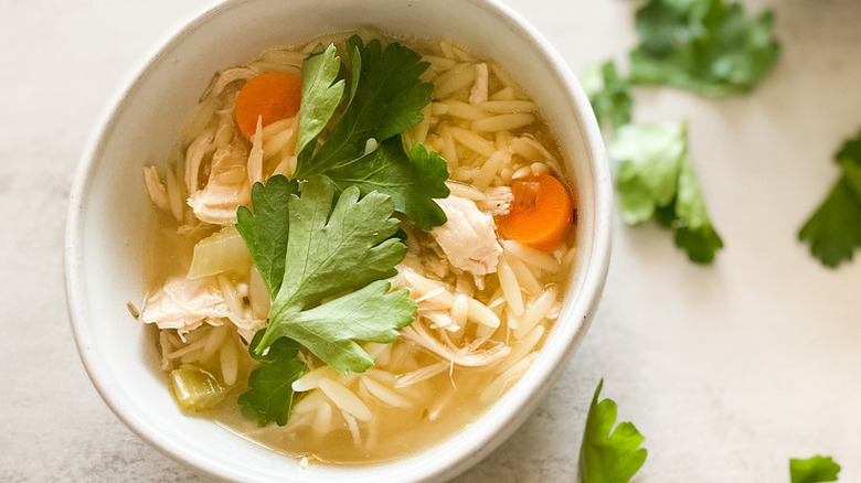 Bowl of lemon chicken orzo soup topped with fresh parsley
