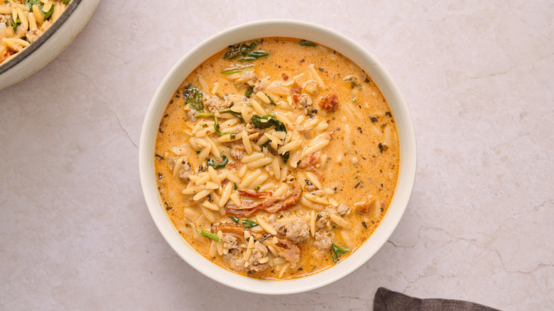 Creamy sausage orzo soup in white bowl