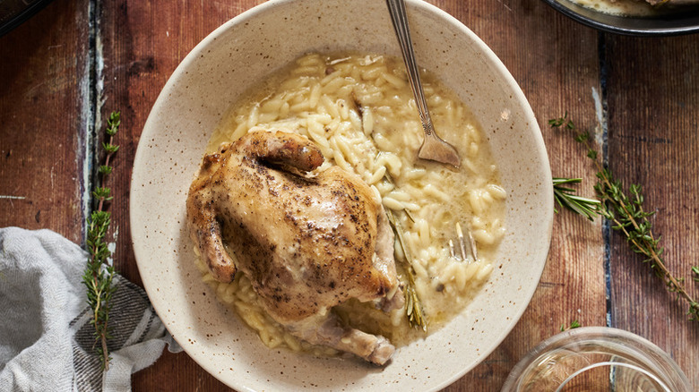 Slow cooked Cornish hen and creamy orzo in bowl with fork