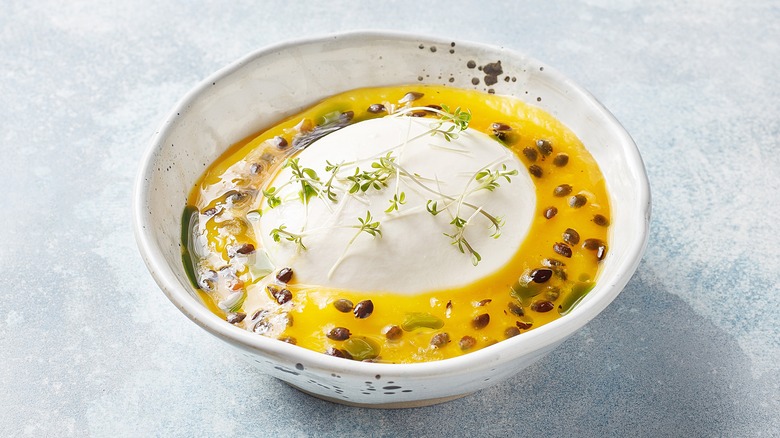 Burrata in bowl with passionfruit sauce and microgreens