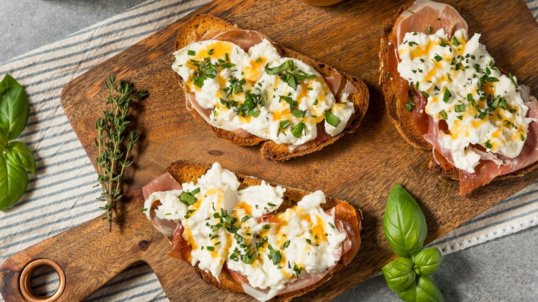 Burrata served on toast with herbs and prosciutto