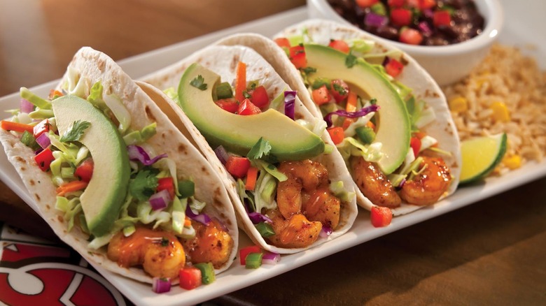 Platter of spicy grilled shrimp tacos with rice and black beans