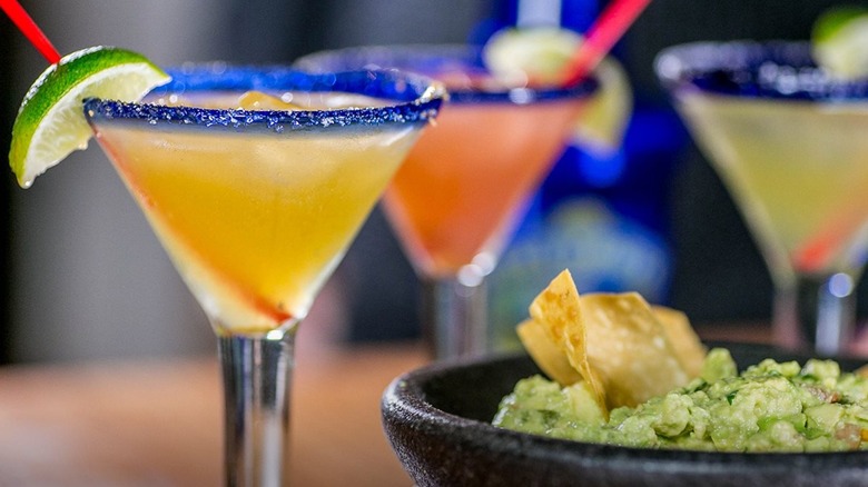 Three flavors of Presidente Margaritas with a bowl of guacamole and chips