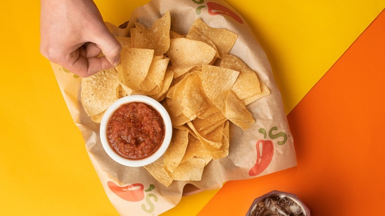 Hand reaching for Chili's chips and salsa
