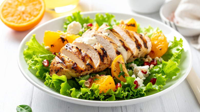Sliced grilled chicken breast on top of a salad