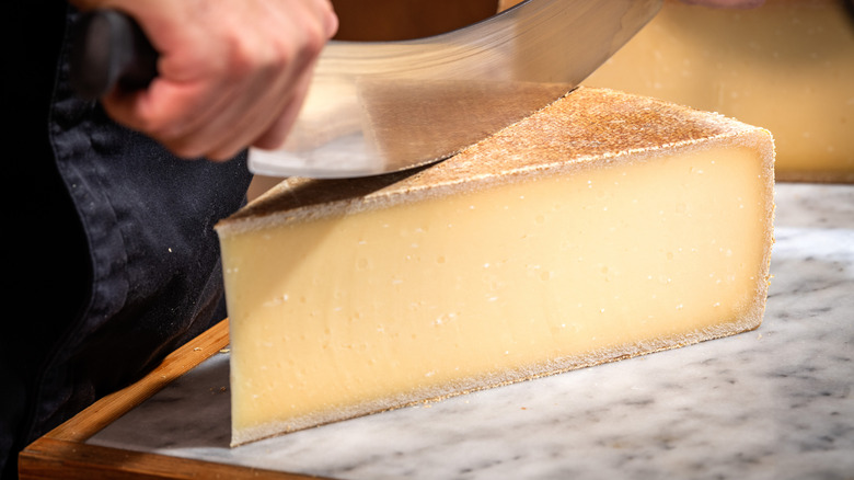 Large wedge of Gruyère cheese being sliced