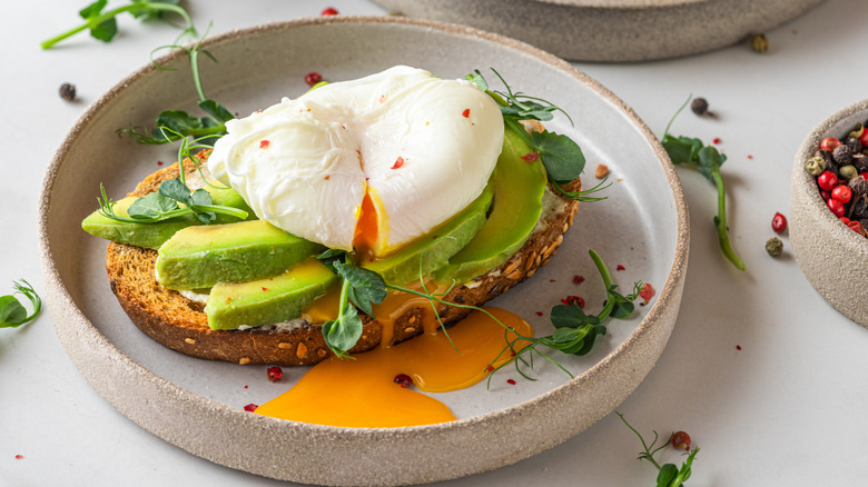 one poached egg dripping yolk onto avocado toast
