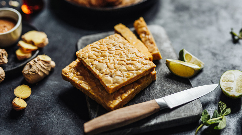 Block of tempeh on a cutting board with ingredients