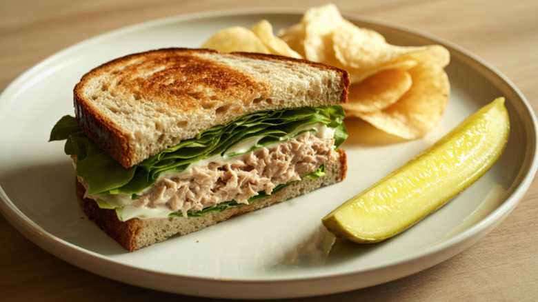 Half a tuna sandwich with pickle and chips