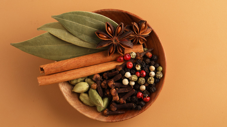 Various whole spices in a wooden bowl