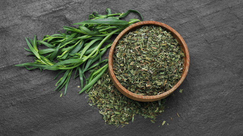 Bunch of fresh tarragon next to a bowl of dry