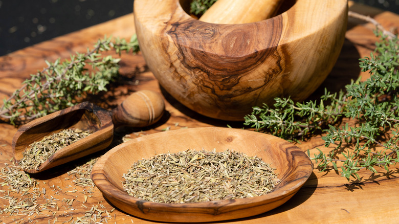 Fresh and dried winter savory in wooden bowls, cutting boards, mortar and pestle, and scoops
