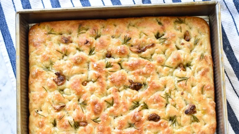 Focaccia bread in a pan on a blue and white striped dishcloth